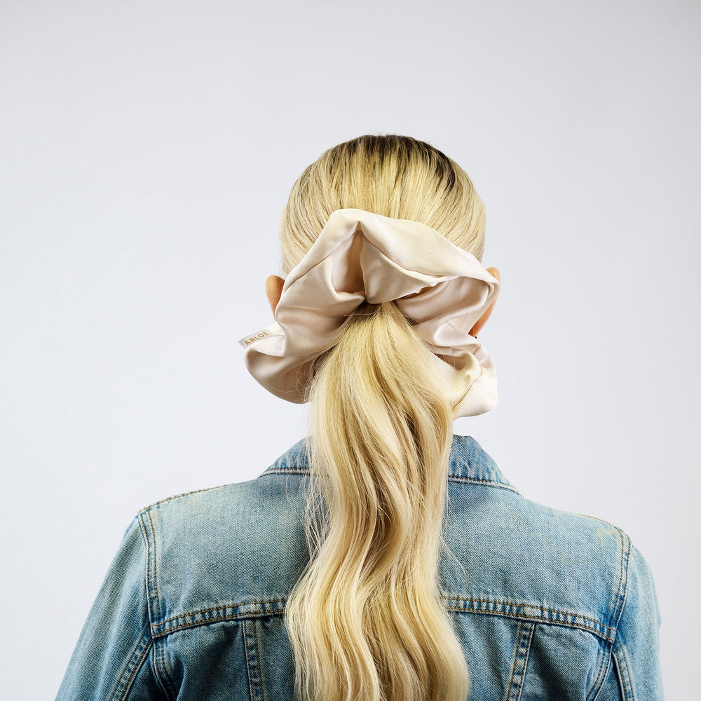 Beige scrunchie with a visible brand tag on a white background
