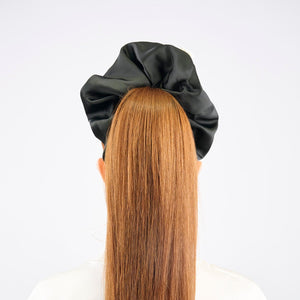 Girl with long red hair wearing a black satin hair bun cover against a white background