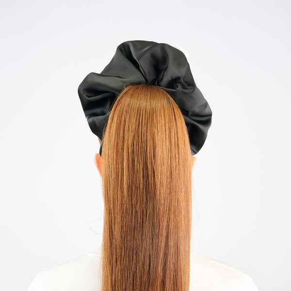 Girl with long red hair wearing a black satin hair bun cover against a white background