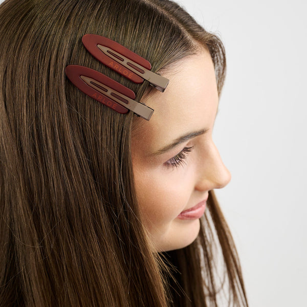 Girl with two red hair clips on her head against a white background