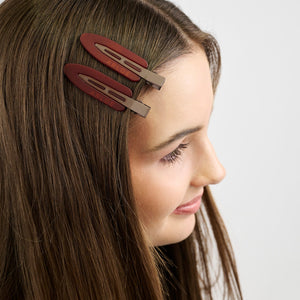 Girl with two brown hair clips on her head against a white background