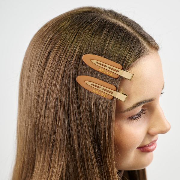 Girl with two light brown hair clips on her head against a white background