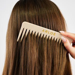 Person brushing their hair with an ARLOE comb