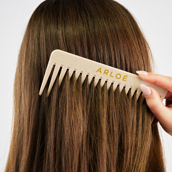 Person brushing their hair with an ARLOE comb