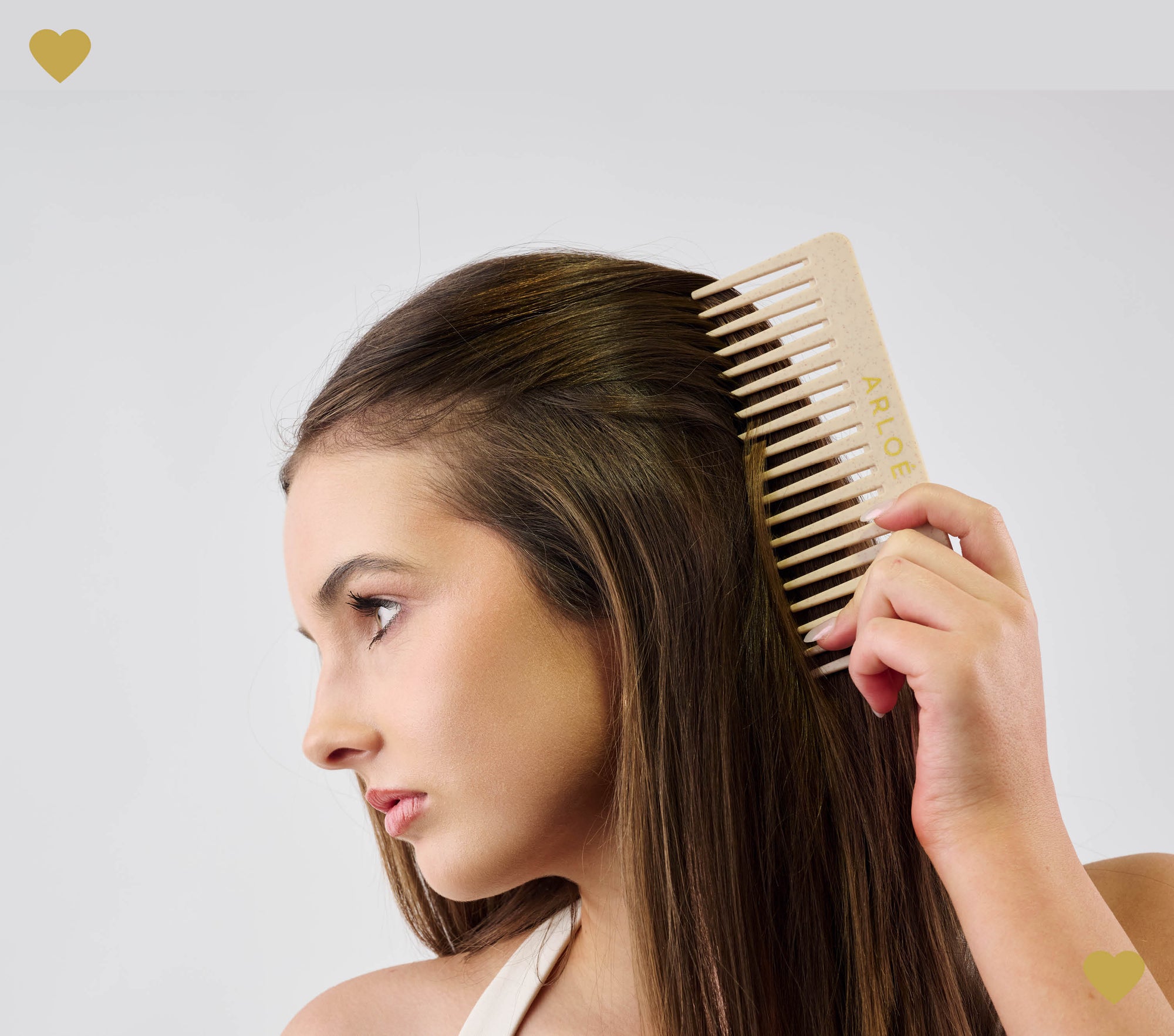Woman combing her hair with a ARLOE comb on a plain background