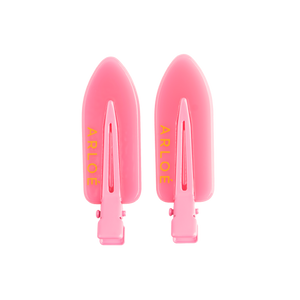Two pink hair clips with ARLOE branding on a white background