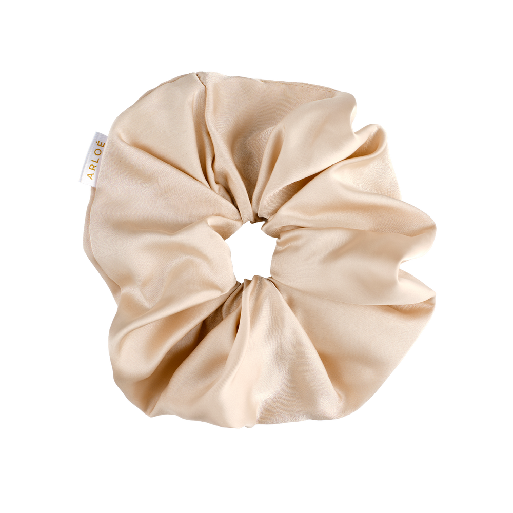 Beige scrunchie with a visible brand tag on a white background
