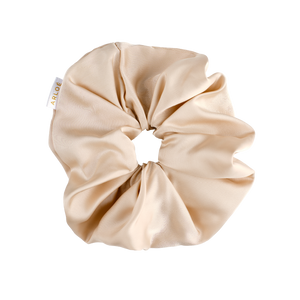 Beige scrunchie with a visible brand tag on a white background
