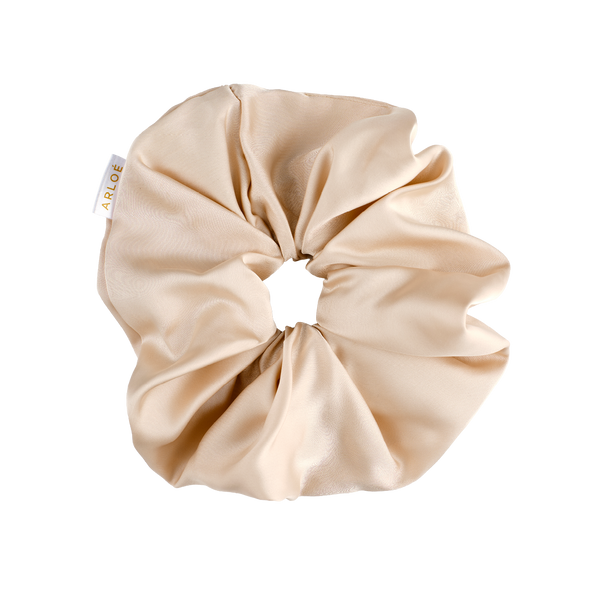 Beige scrunchie with a visible brand tag on a white background