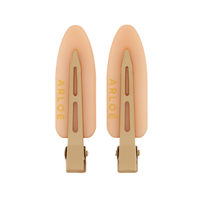 Two peach-colored hair clips with gold accents on a white background, branded 'ARLOE'.