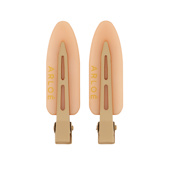 Two peach-colored hair clips with gold accents on a white background, branded 'ARLOE'.